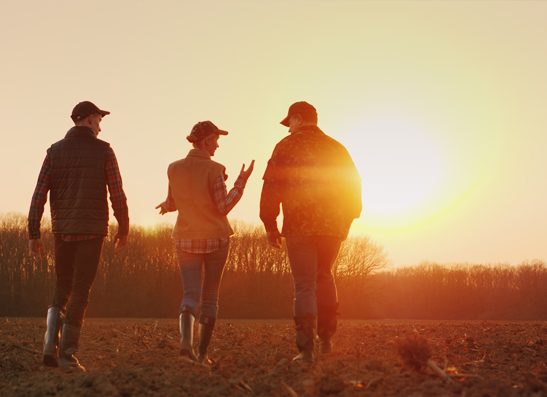 Commercial Umbrella - Three Farmers Walking Together on a Plowed Field at Sunset